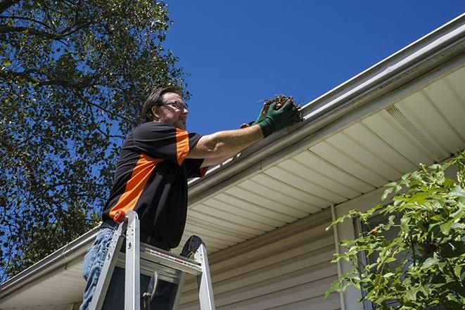 smiling worker fixing gutters on a residential home in Bloomfield